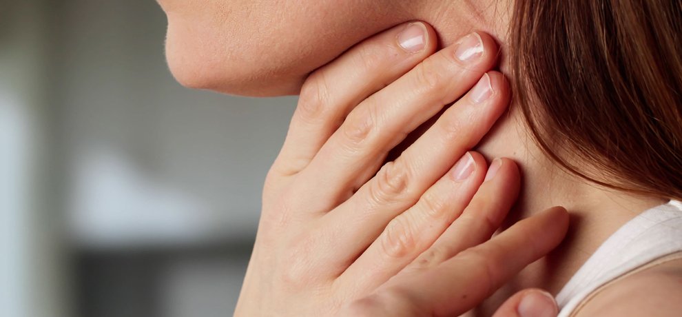 Femme sereine une main posee sur la gorge sur fond beige neutre, lumiere douce naturelle