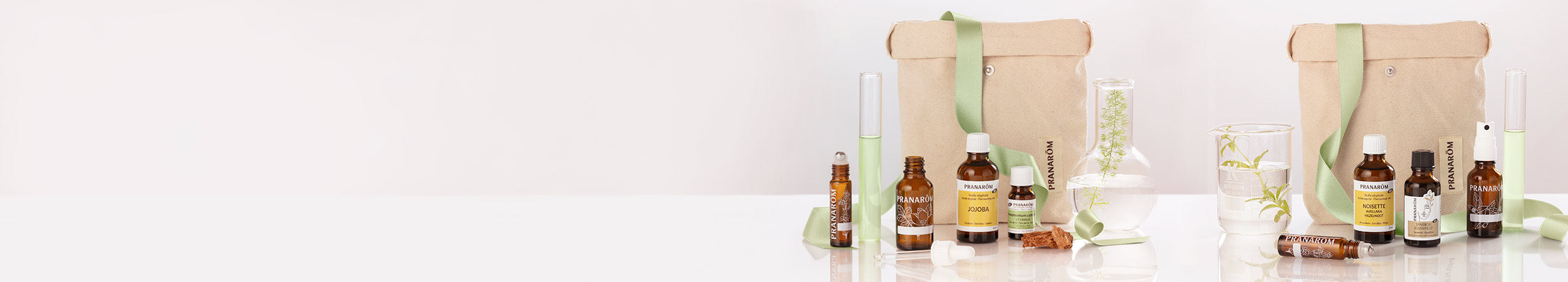 Bannière avec différents produits de coffrets Pranarōm : contenants et huiles végétales de jojoba.