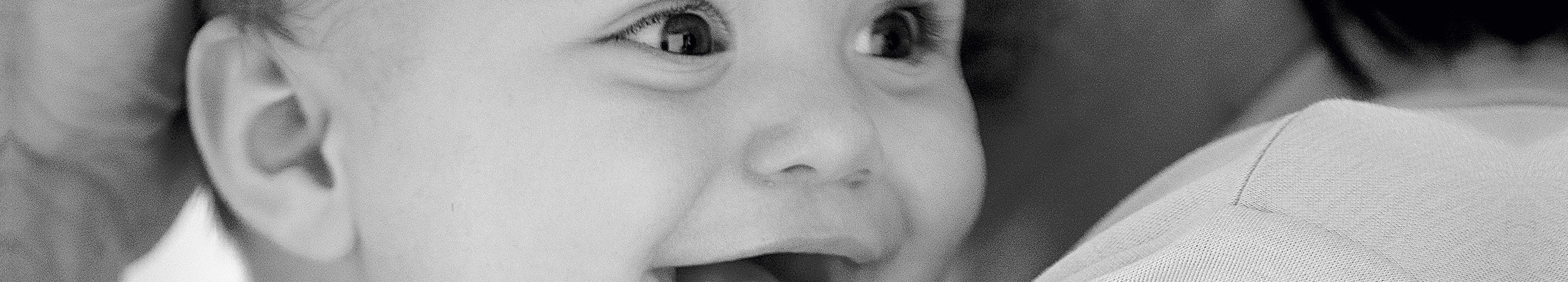 Bébé souriant en gros plan dans les bras d'une personne.