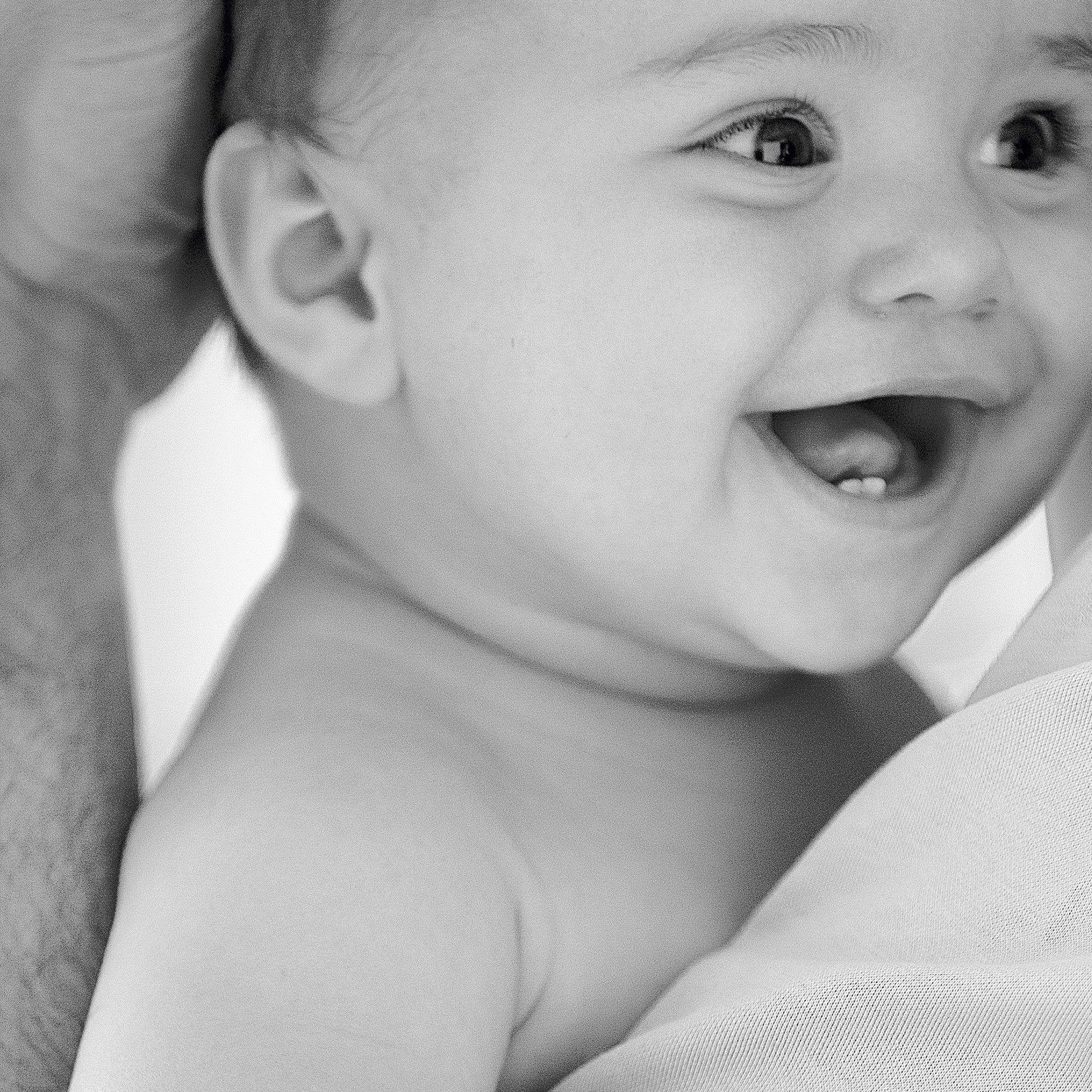 Un bébé souriant qui est tenu dans les bras.