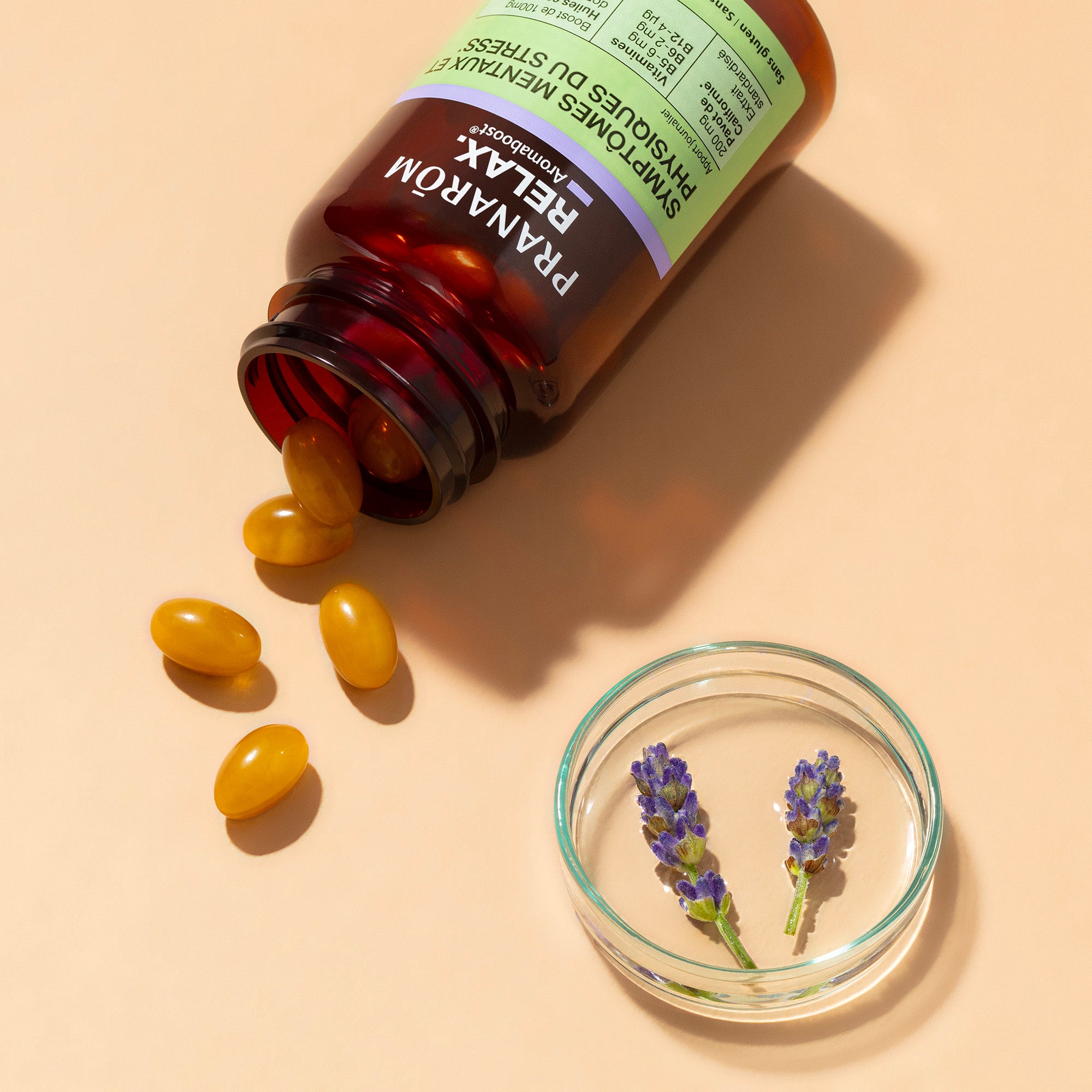 Flacon Aromaboost Relax de Pranarôm, renversé avec capsules jaunes et lavande.