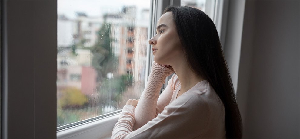 Femme sereine baignee de lumiere naturelle douce le matin en hiver, symbole de bien-etre emotionnel retrouve